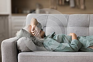 Calm senior sleepy woman napping at home, lying on back