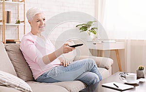 Calm senior woman watching tv at home