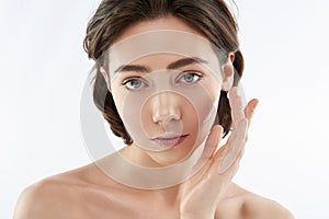 Calm sensual woman applying cream on face