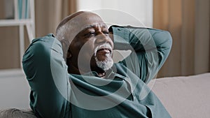 Calm serene elderly adult African American man relaxing with eyes closed take break relax at home office, old grandpa