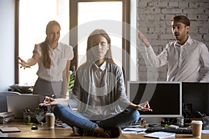 Calm serene employee meditating in office ignoring annoying coll