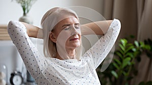 Calm serene mature woman resting with eyes closed at home