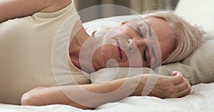 Calm serene mature woman resting sleeping well in comfortable bed