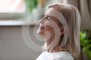 Calm serene middle aged woman breathing with eyes closed