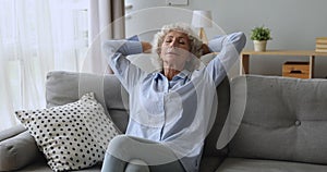 Calm serene old woman resting on sofa with eyes closed