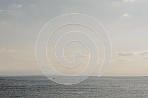 Calm sky and sea at sunset, unidentified boat in the distance