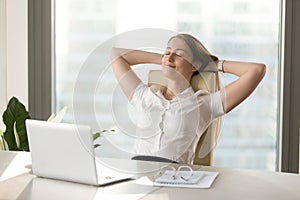 Calm smiling businesswoman relaxing at comfortable chair hands b