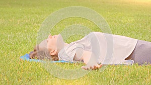Calm smiling woman with long flowing hair resting on green grass