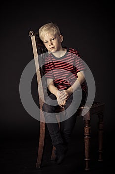 Calm thoughtful little boy sitting on a chair