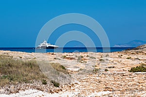 calm torquoise Balearic sea in the sunny day with luxurious boat arriving to the Formentera beach