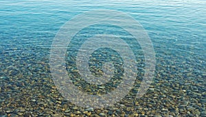 A calm transporent water surface with pebbles stone under water surface