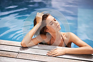 Calm, vacation and woman relax in swimming pool and rest on deck with peace at hotel or home. Summer, holiday and girl