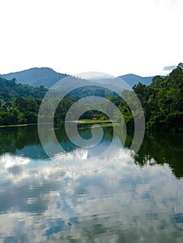 Calm view of dam water surrounded with green trees in Kuala Kubu Bharu, Selangor, Malaysia.