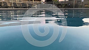 Calm water ripples softly at a hotel pool at sunset