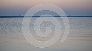 Calm water surface of a lake or river at dusk with colorful sky