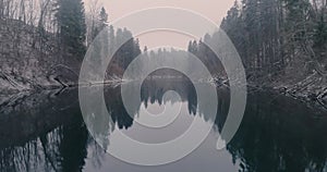 Calm water of a winter forest river in the cold early morning.