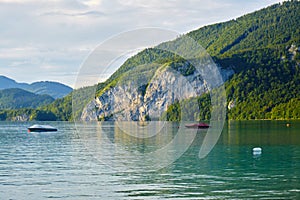 Calm waters of Wolfgang lake Wolfgangsee Austria, in the golden light of the sunset, with a couple of boats anchored.