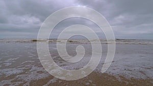 Calm waves coming towards the camera view in a lonely beach during a cloudy day