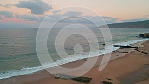 Calm waves crashing shoreline drone view. Cloudy sunset illuminating coastline