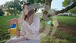 Calm woman enjoy water in park sitting picnic blanket at evening closeup