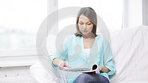 Calm woman reading magazine and sitting on couch