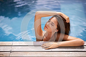 Calm, woman and relax in swimming pool on vacation and rest on deck with peace at hotel or home. Summer, holiday and