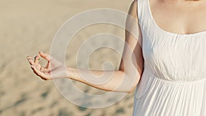 Calm woman relaxing, meditating on summer sand beach alone. Girl calms down, breathes deeply with mudra om. Inner peace