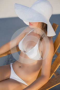 Calm woman in straw hat relaxing in deck chair on the beach