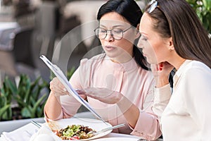 Calm women choosing dish at table