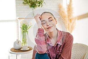 Calm young caucasian woman sitting on a comfortable chair and enjoying