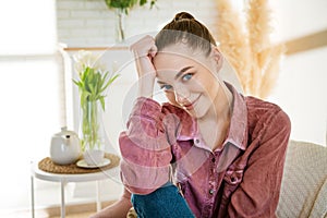 Calm young caucasian woman sitting on a comfortable chair and enjoying