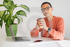 Calm young latin lady enjoy peace and free time, planning day, drink cup of coffee at table