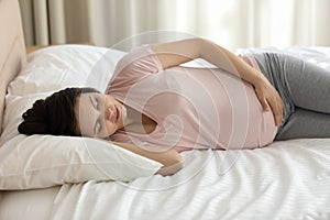 Calm young pregnant woman resting in bed, sleeping peacefully