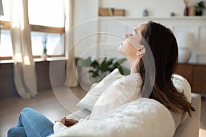 Calm young woman relax on sofa breathing fresh air