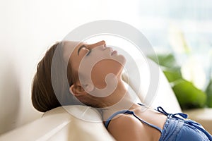 Calm young woman relaxing on cozy sofa, breathing fresh air