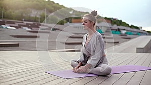 Calm young woman sitting on yoga mat with closed eyes and meditating in butterfly pose, tilting head forward.