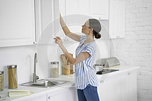 Woman opening the kitchen cupboard stock photo photo