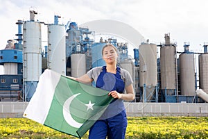 Calm young woman worker with flag of Pakistan against background of factory