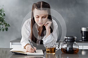 Calm young woman writing in her diary