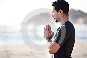 Calm your mind. Cropped shot of a handsome young male athlete meditating on the beach.