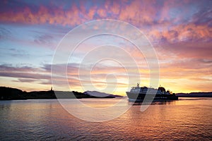 A Calmac ferry entering Oban harbour in the Scottish highlands during sunset
