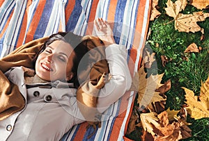 Calmly smiling woman lying on the grass in autumn park