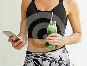 Calorie counting application. Slim woman holding a bottle of broccoli and spinach smoothie