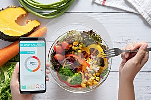 Calories counting , diet , food control and weight loss concept. Calorie counter application on smartphone screen at dining table