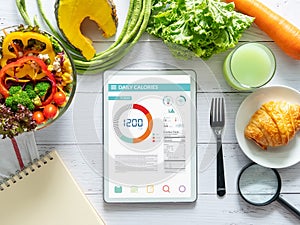 Calories counting , diet , food control and weight loss concept. tablet with Calorie counter application on screen at dining table