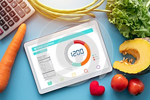 Calories counting , diet , food control and weight loss concept. tablet with Calorie counter application on screen at dining table