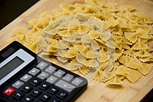 Calulator with pasta on wooden background, calories