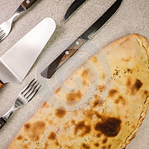 Calzone pizza on table and different cutlery