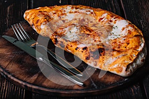 Calzone - Stuffed Pizza. Fork and knife on the cutting board