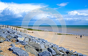 Camber sands beach in England, UK. Sand and rock beach in Britain. Group of rocks in sea front beach. Dog walking.